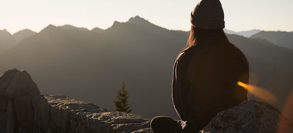 Girl sitting alone on a mountain meditating. 